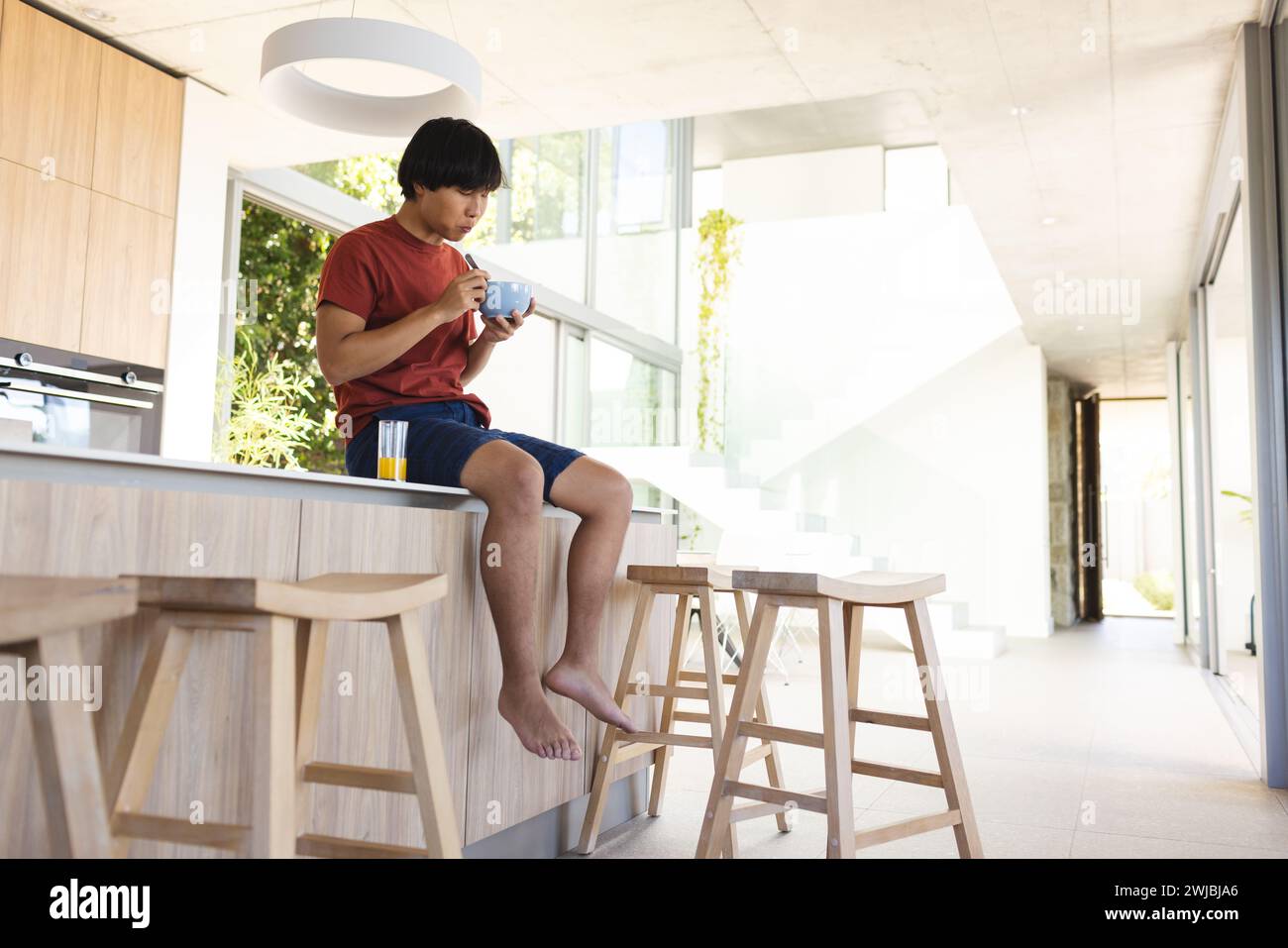 Teenager asiatischer Junge genießt einen Snack zu Hause, mit Kopierraum Stockfoto