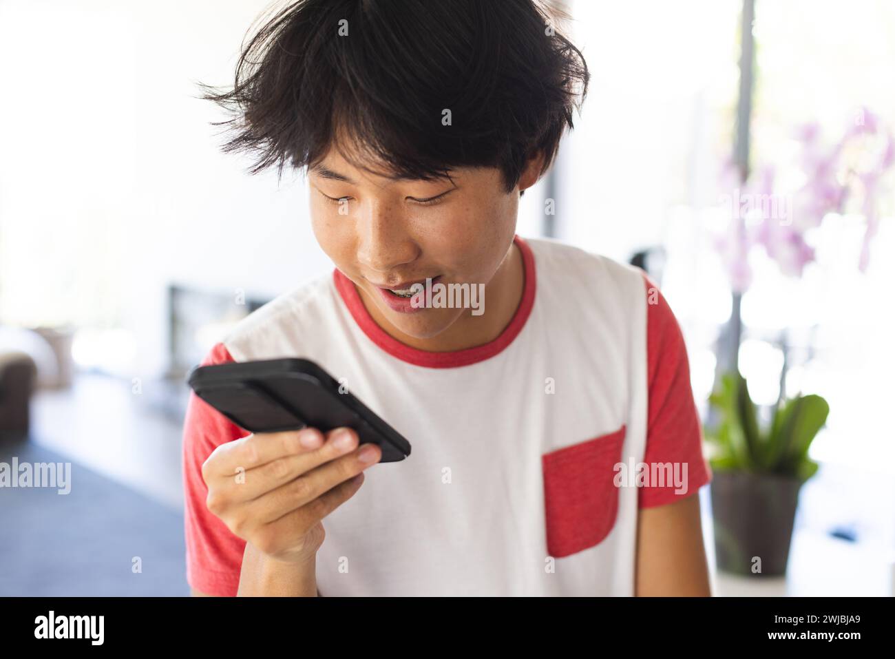 Teenager asiatischer Junge, der zu Hause ein Smartphone benutzt, mit Kopierraum Stockfoto