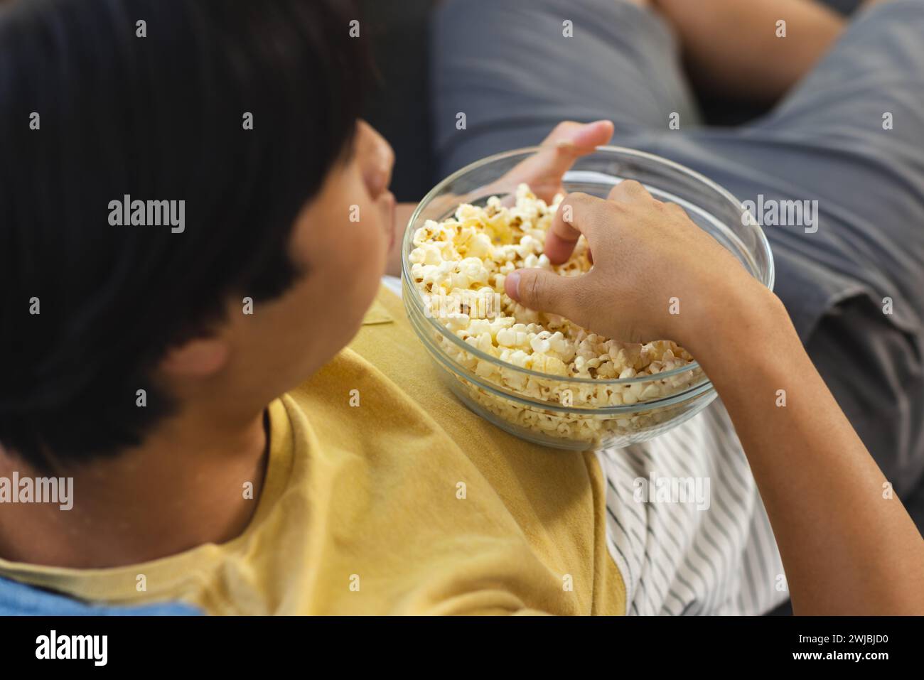 Teenager Asiatischer Junge genießt zu Hause eine Schüssel Popcorn Stockfoto