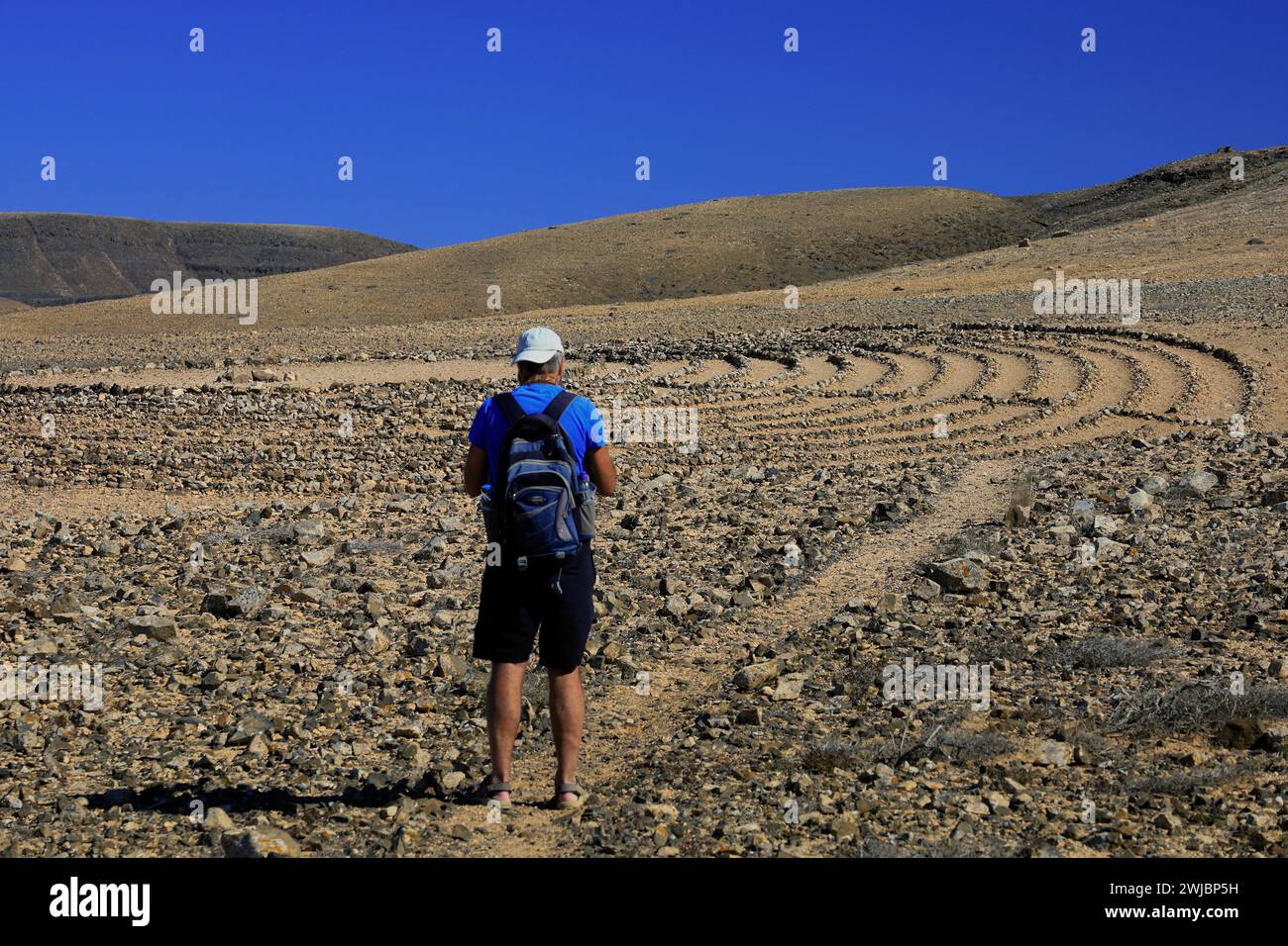 Mann besucht Wolf Pattons Labyrinth - niedriges Steinlabyrinth mitten im Nirgendwo in der Nähe von El Cotillo, Fuerteventura. Vom November 2023 Stockfoto