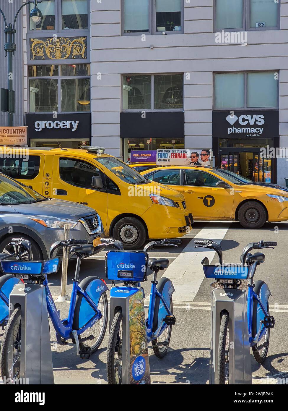 NEW YORK, USA - 8. MÄRZ 2020: Gelbe Taxis und Fahrräder zusammen, traditionelle lokale Verkehrssymbole, auf einer Manhattan Street. Stockfoto