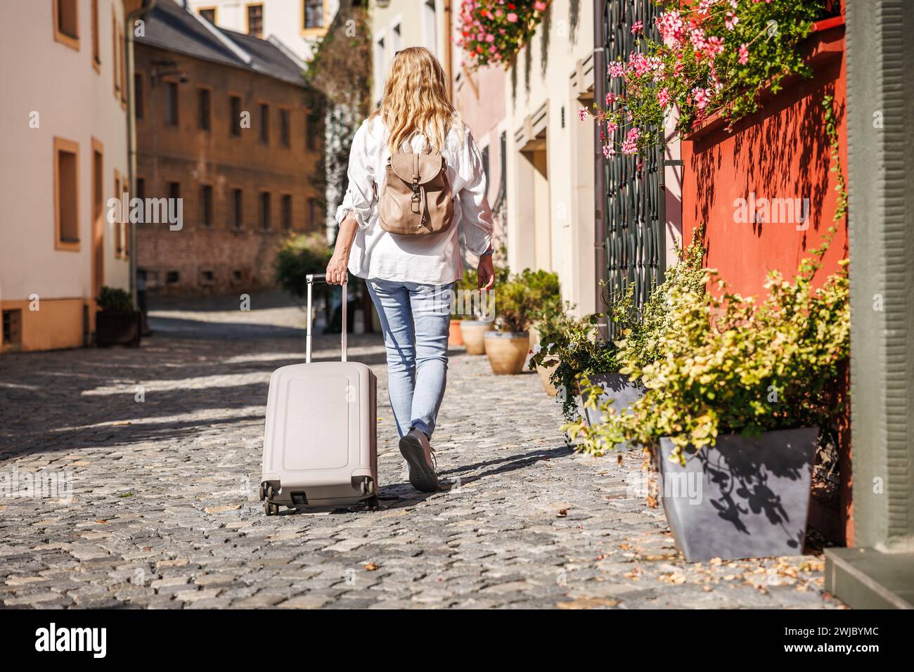 Frau Touristin mit Koffer und Rucksack, die auf der Straße in Olomouc, Tschechien, läuft. Alleinreisende Stockfoto