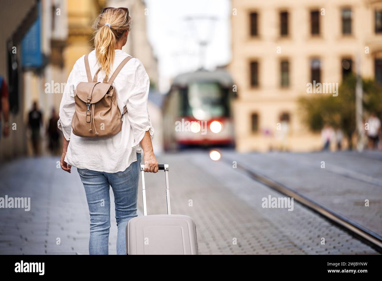 Alleinreisende. Frau, die mit dem Rucksack den Koffer zieht und auf der Straße läuft. Reise und Urlaub in der europäischen Stadt Olomouc, Tschechische Republik Stockfoto