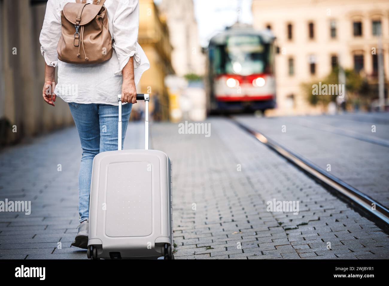 Alleinreisende. Frau, die mit dem Rucksack den Koffer zieht und auf der Straße läuft. Reise und Urlaub in der europäischen Stadt Stockfoto