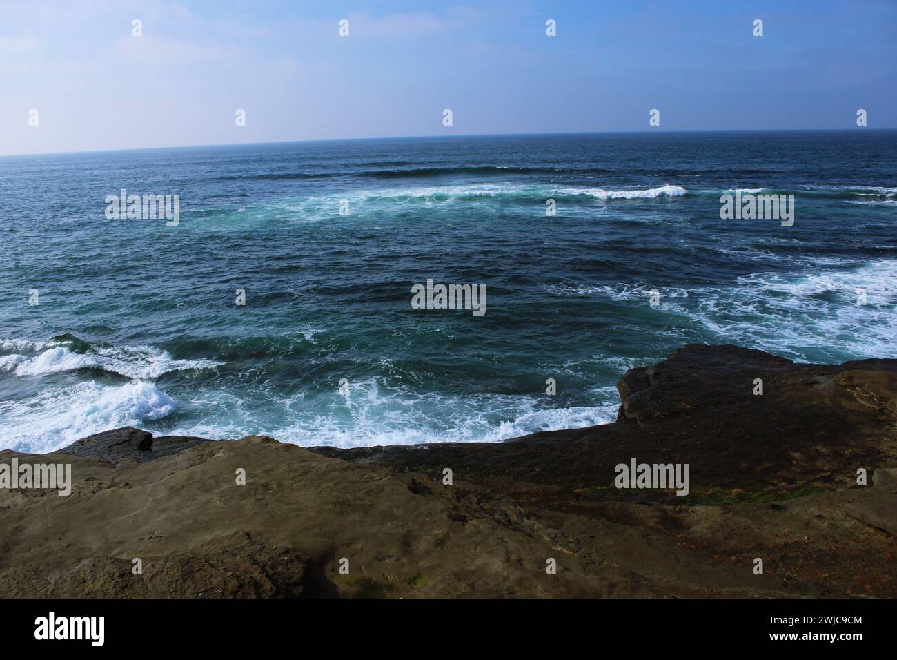 Die schäumenden Wellen des Ozeans treffen das felsige Ufer mit dem Horizont im Hintergrund Stockfoto