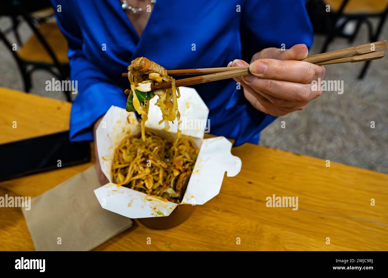 Frau isst Nudeln mit Gemüse und Fleisch aus Chinesen. Stockfoto