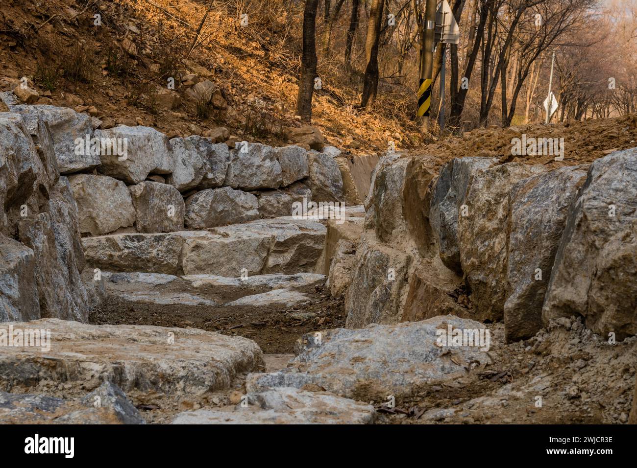 Entwässerungsgraben aus großen Felsblöcken am frühen Frühlingnachmittag in Südkorea Stockfoto