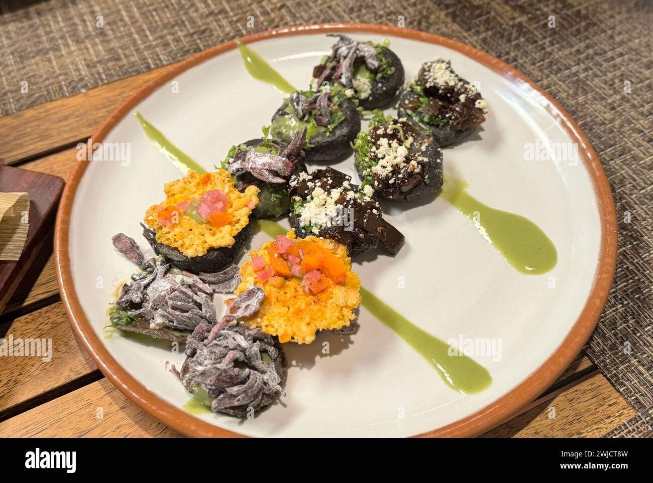 Elegant plattierte Gourmet-Huchepos mit Huitlacoche und Kürbisblüten, akzentuiert mit Avocado und einem Hauch grüner Sauce. Stockfoto