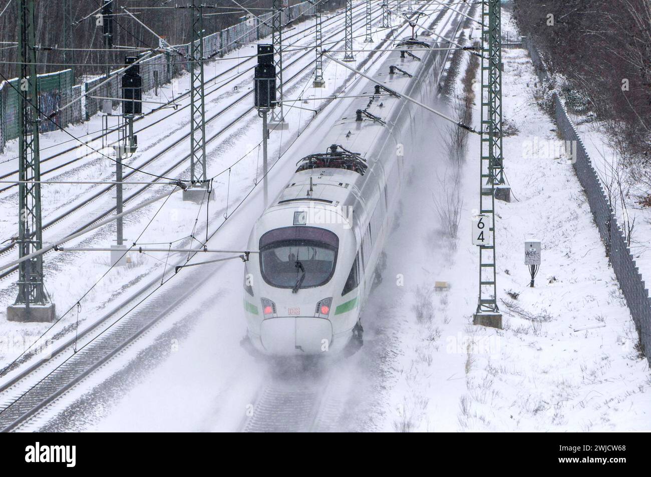 Ein ICE-Zug der Deutschen Bahn fährt über verschneite Gleise und wirbelt Schnee auf, Berlin, 09.02/2021 Stockfoto