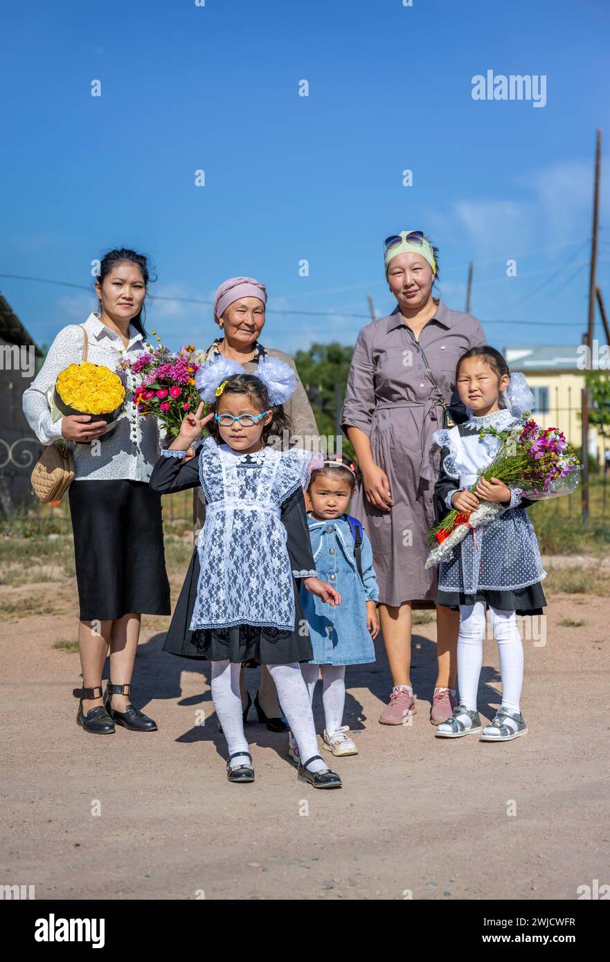 Familie und Schulmädchen mit einem Blumenstrauß am ersten Schultag, Region Issyk-Kul, Kirgisistan Stockfoto