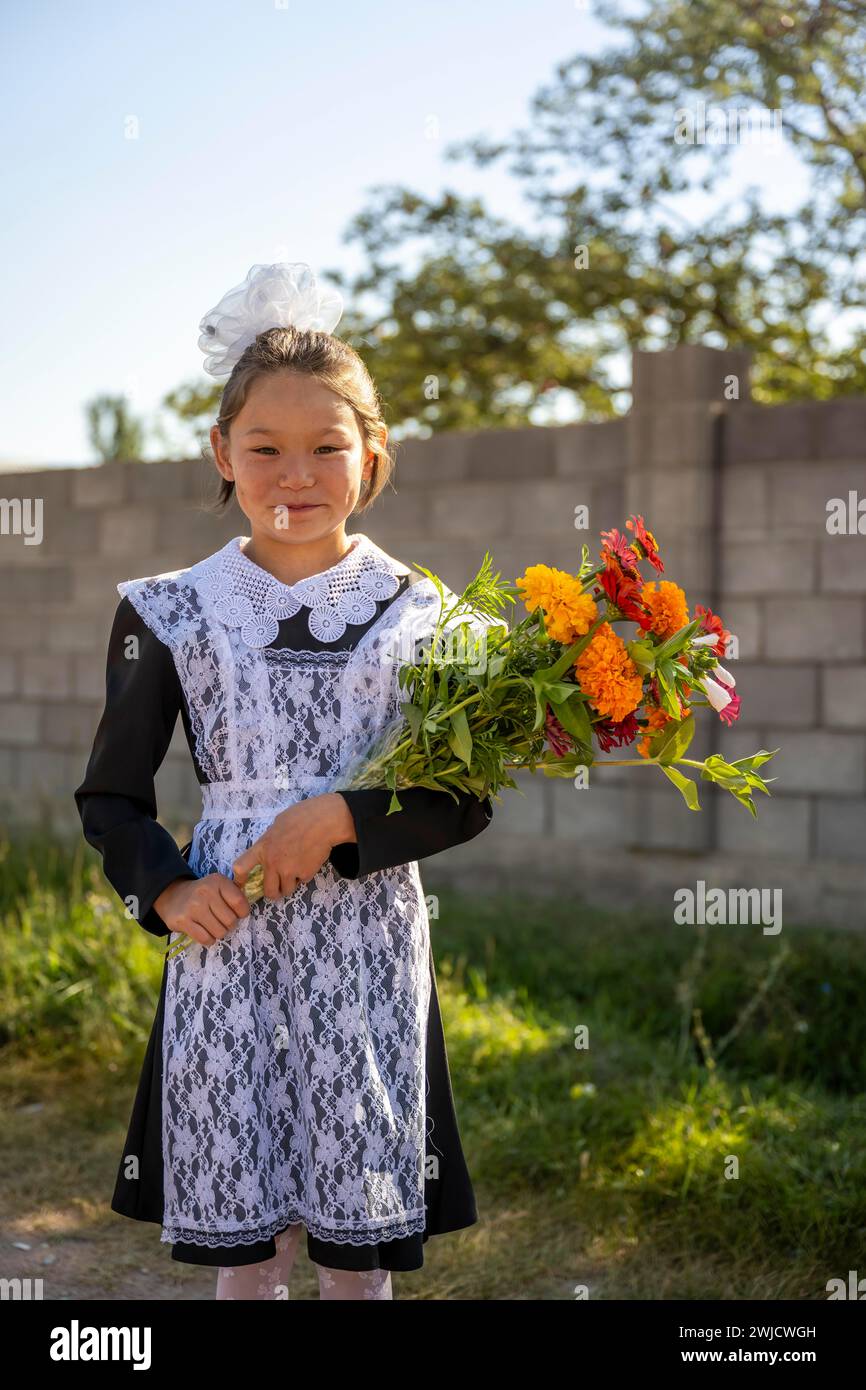 Schulmädchen mit einem Blumenstrauß an ihrem ersten Schultag in der Region Issyk-Kul, Kirgisistan Stockfoto