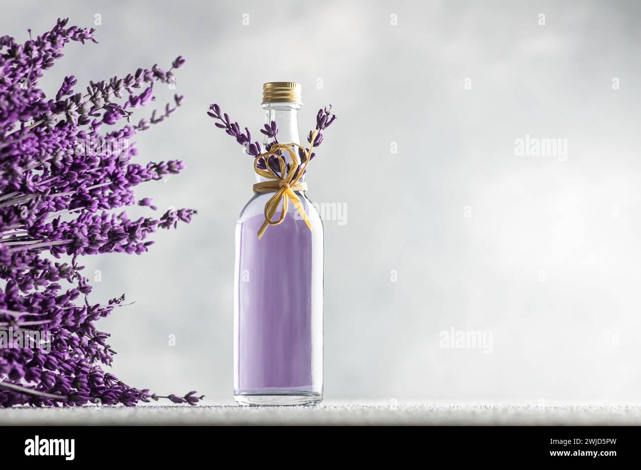 Glasflasche ätherisches Lavendelöl mit getrockneten Lavendelblüten und Samen, Aromatherapie-Spa-Massagekonzept. Lavendula oleum Stockfoto