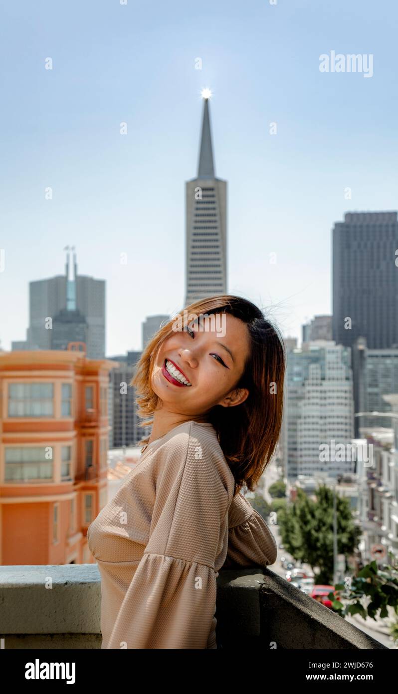 Teenager Chinesisches Mädchen lächelnd vor dem San Francisco Skyline Transamerica Gebäude Stockfoto