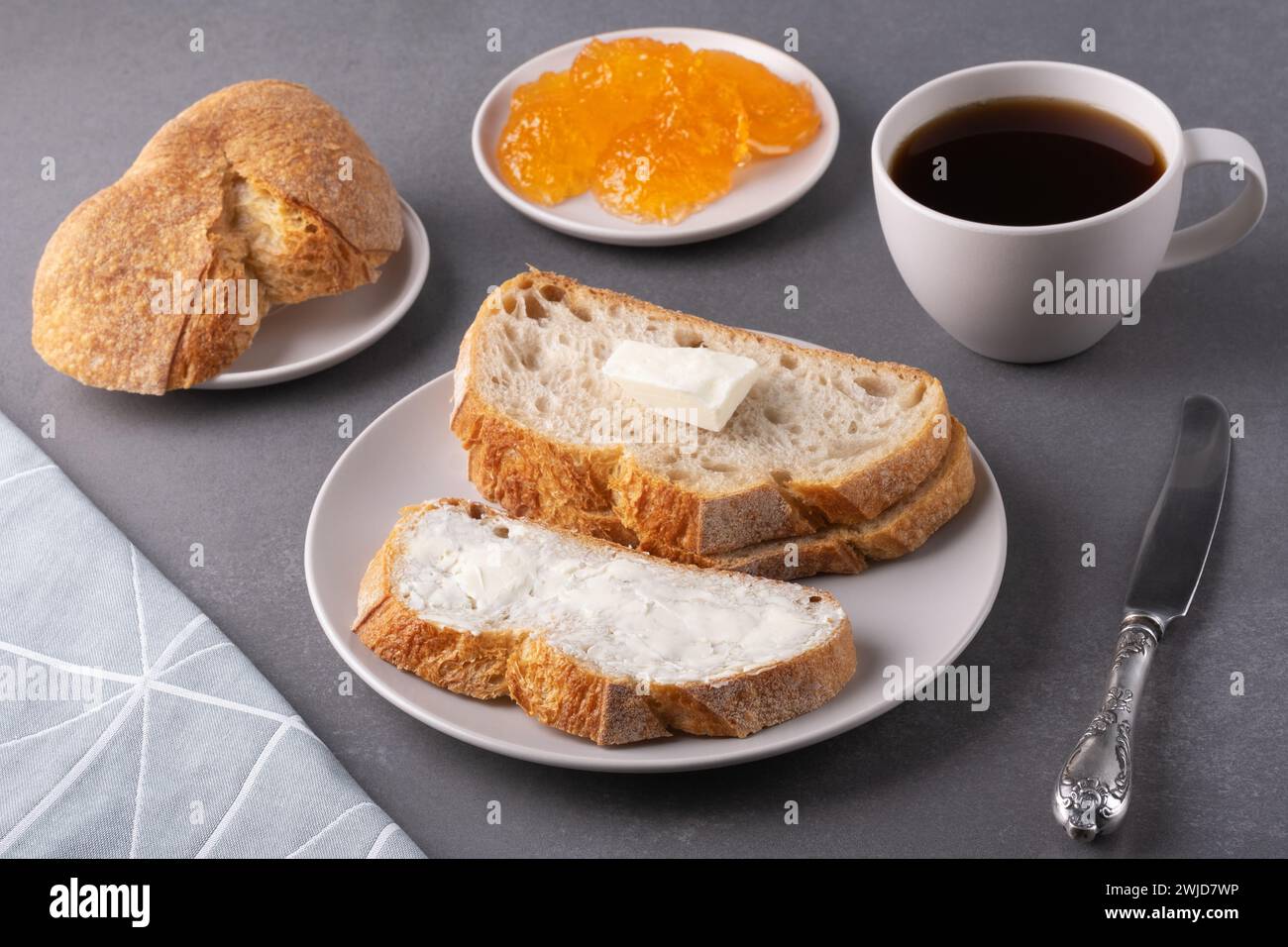 Sandwiches mit Butter, einer Tasse Kaffee und Aprikosenmarmelade auf grauem Hintergrund Stockfoto