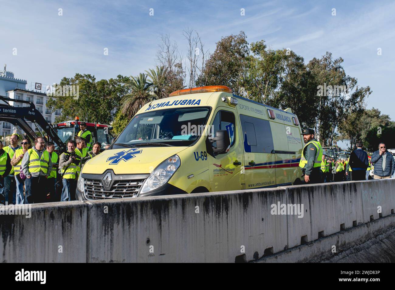 Ein Krankenwagen versucht, durch die Streiklinie der Bauern auf der Autobahn A49 zu gelangen. Andalusische Bauern haben alle Autobahnen blockiert, die nach Sevilla führen. Diese Proteste werden zum Teil von Gewerkschaften und landwirtschaftlichen Organisationen der extremen Rechten Spaniens gefördert, die die Probleme der Landwirte zum Ziel haben und dann Druck auf die Regierung ausüben. Diese Proteste finden seit dem 6. Februar in Spanien statt, als Reaktion auf die Proteste in Frankreich, wo sich die Landwirte über unlauteren Wettbewerb mit Produkten aus Drittländern, die europäische Agrarpolitik und die niedrigen Gewinne beklagen Stockfoto