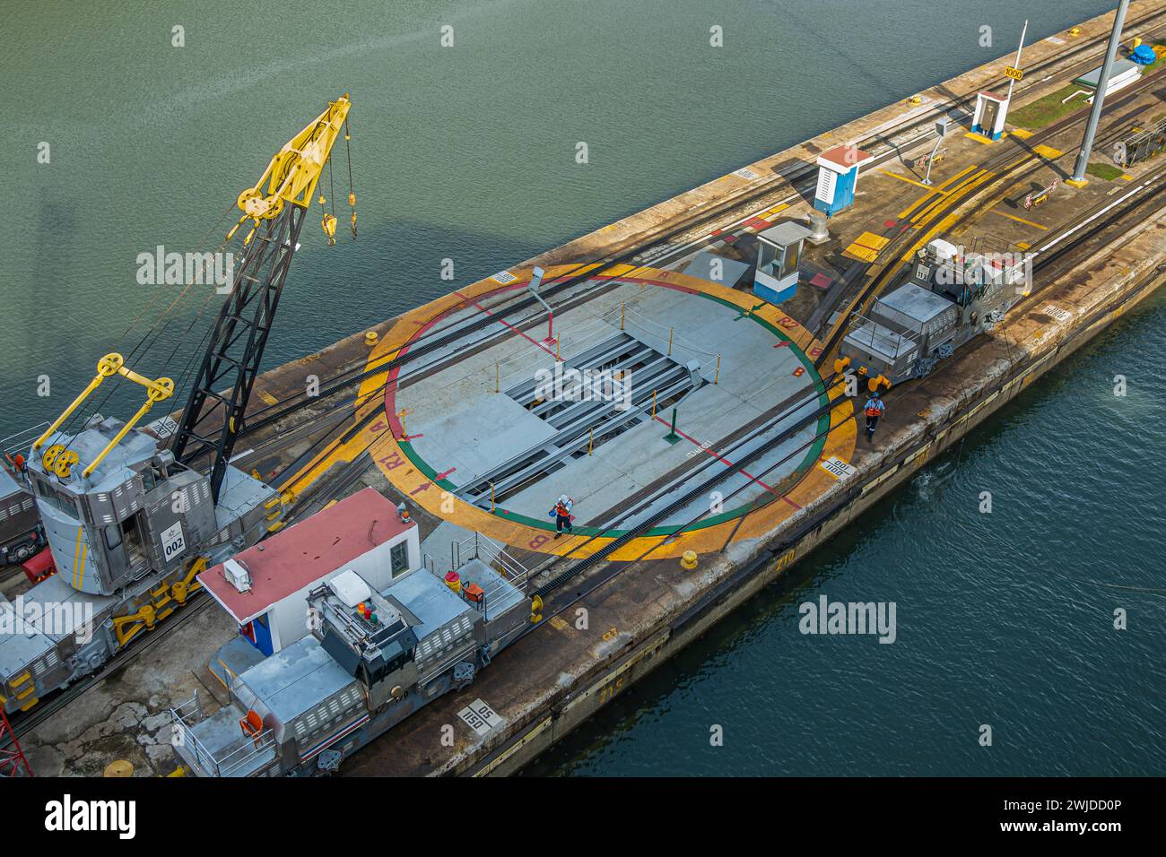 Panamakanal, Panama - 24. Juli 2023: Nahaufnahme, Miraflores versperrt die Kammer-Trennpier, Maschinen, die ein Schiff in eine Schleusendrehplatte ziehen. Arbeiter und Stockfoto