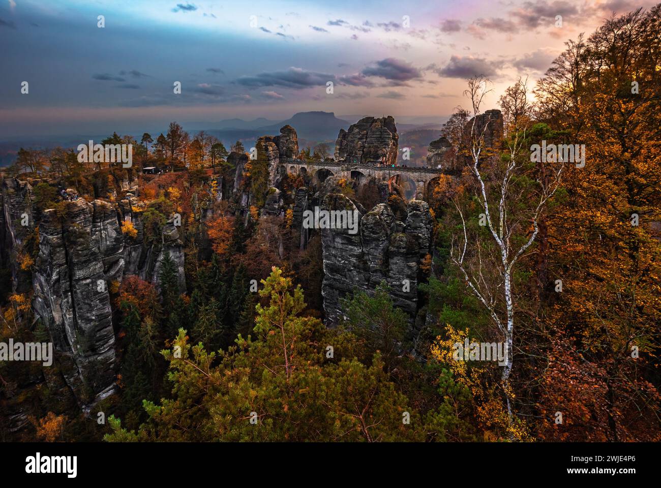 Sächsisch, Deutschland - die Bastei-Brücke mit einem sonnigen Herbstsonnenaufgang mit farbenfrohem Laub und Himmel. Bastei ist berühmt für die wunderschöne Felsformation in Sax Stockfoto
