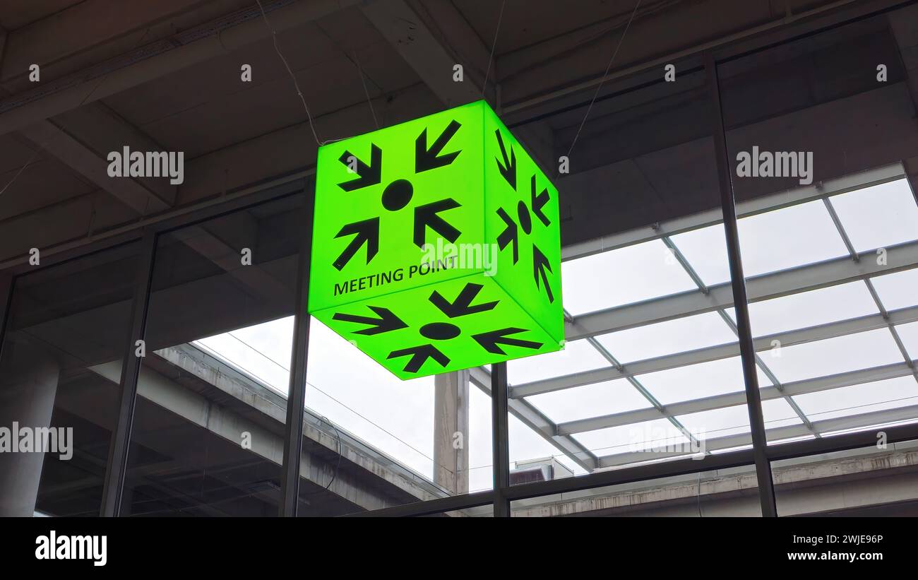 Schild mit Treffpunkt an einem Gebäude. Das Hotel befindet sich in der Nähe des Eingangs und dient als visueller Hinweis, der die Einzelpersonen in Richtung des zentralen Tagungsbereichs lenkt Stockfoto