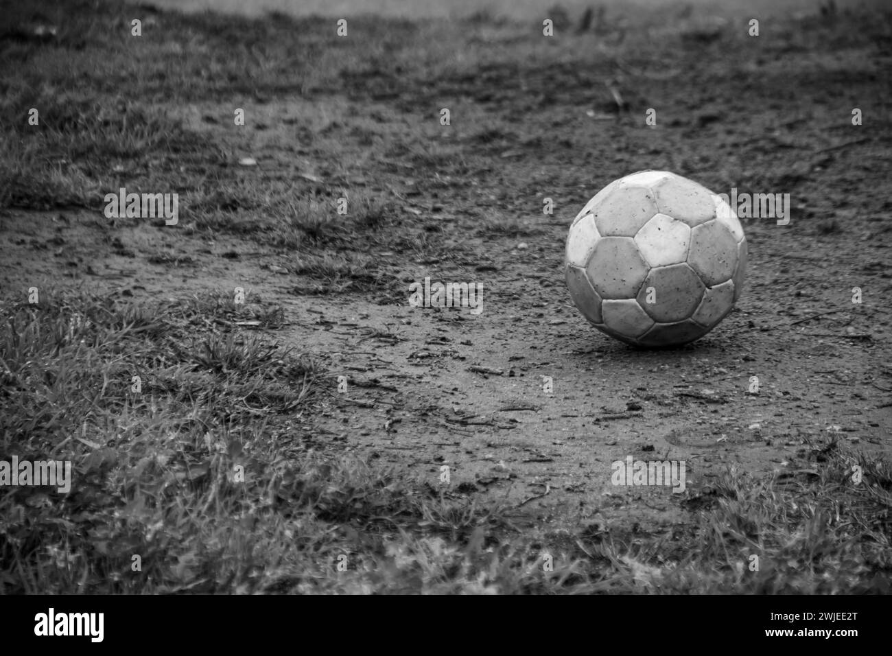 Ein einsamer schwarz-weißer Fußball, der auf einem leeren Feld liegt Stockfoto