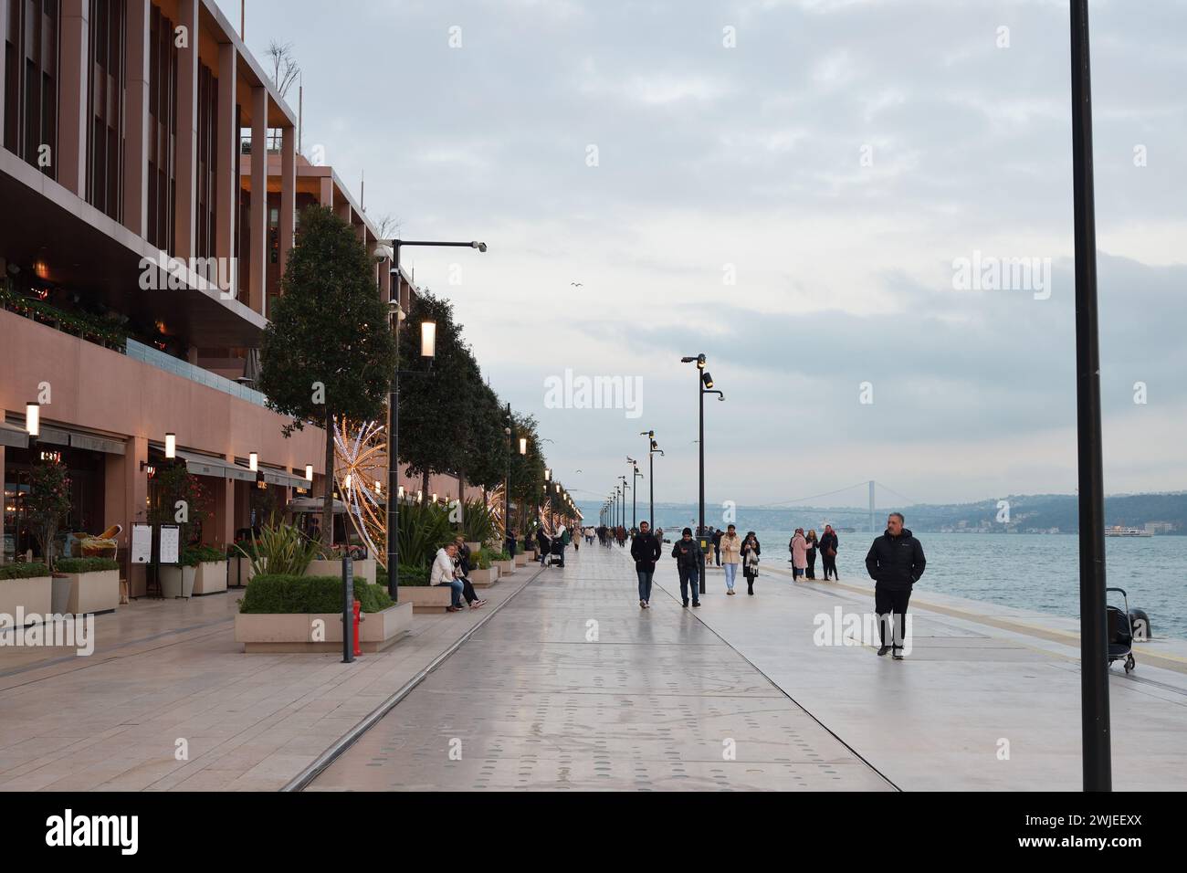 Istanbul, Türkei - 11. Dezember 2023: Die Menschen spazieren abends auf dem Stadtdamm. Galataport Promenade Stockfoto
