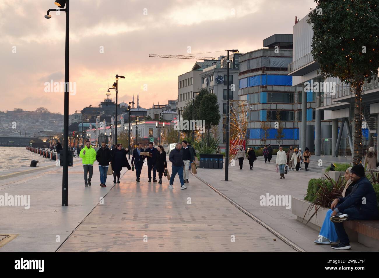 Istanbul, Türkei - 11. Dezember 2023: Die Menschen spazieren abends auf dem Stadtdamm. Galataport Promenade Stockfoto