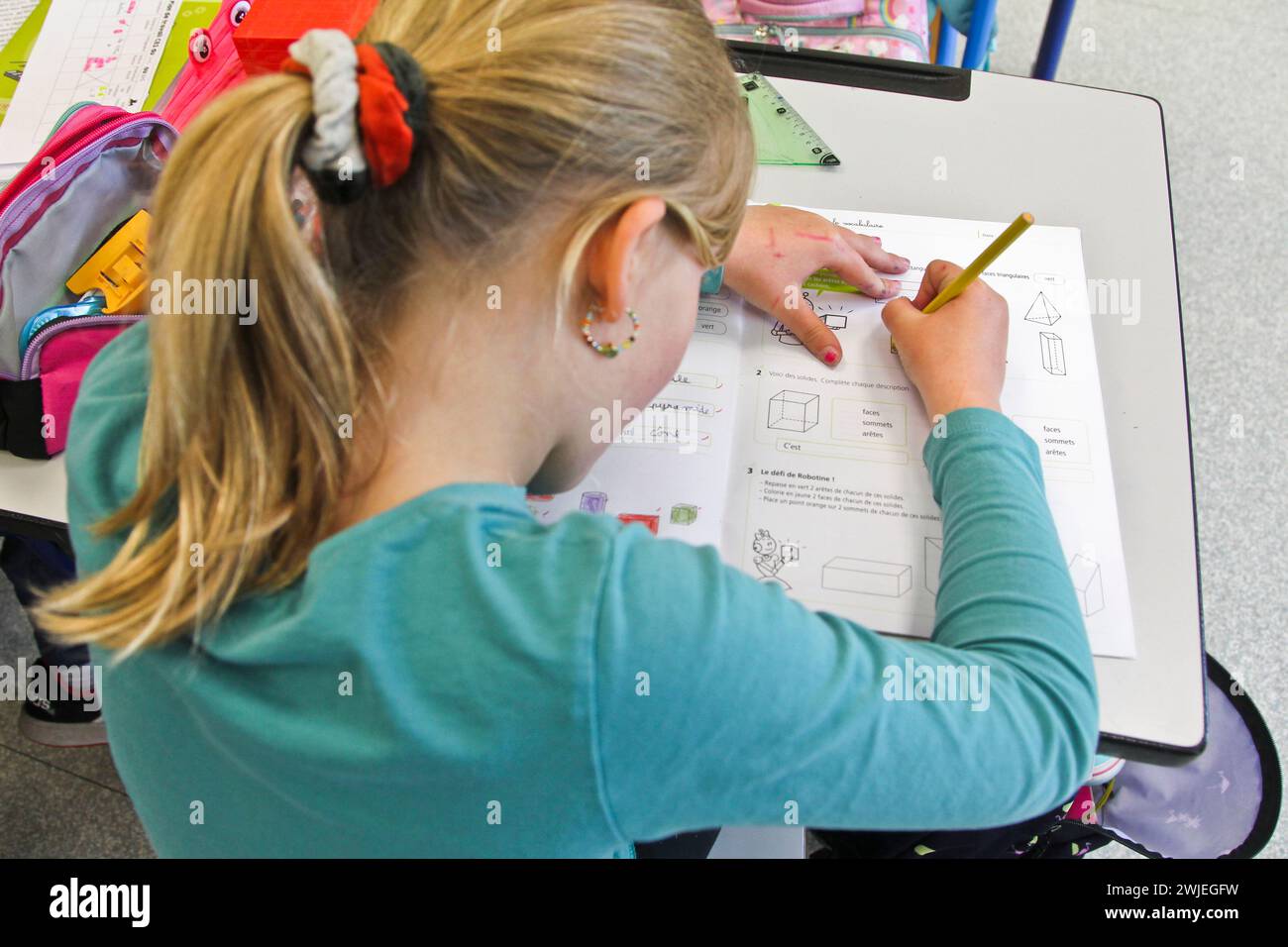 Arvieux, Departement Hautes-Alpes (Französische Alpen), Queyras: Grundschulklasse. Das Schulmädchen sitzt an ihrem Schreibtisch und schreibt in ihr Mathematik-Arbeitsbuch Stockfoto