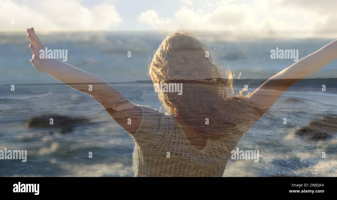 Frau lockert Haare, blickt auf den Strand mit Wellen Stockfoto