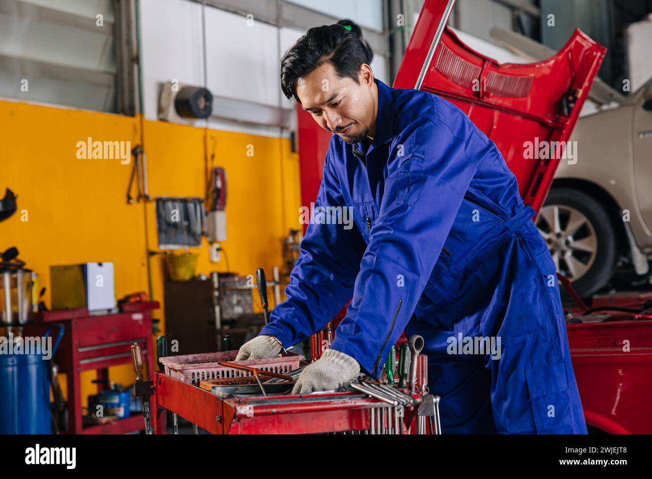 Asiatische japanische männliche Mechaniker Arbeiter Porträt in Auto Service Werkstatt Auto Wartung Center ersetzen Fix Auto Motor Teil Stockfoto