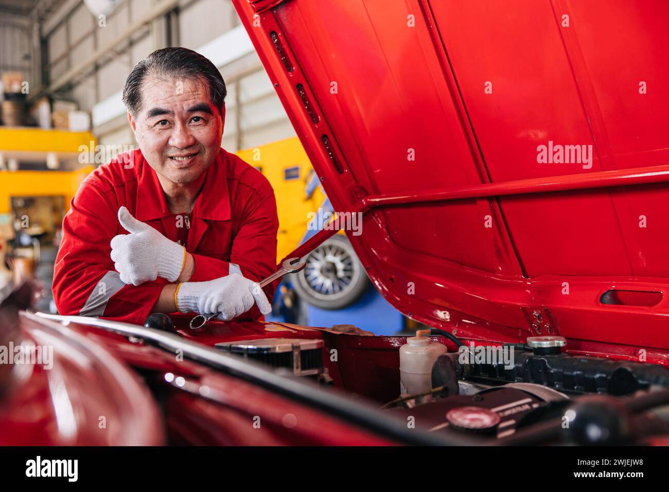 Glückliche Senior professionelle asiatische männliche Mechaniker Garage Arbeiter glückliche Arbeit ersetzen Wartung Auto Service in der Autowerkstatt Stockfoto