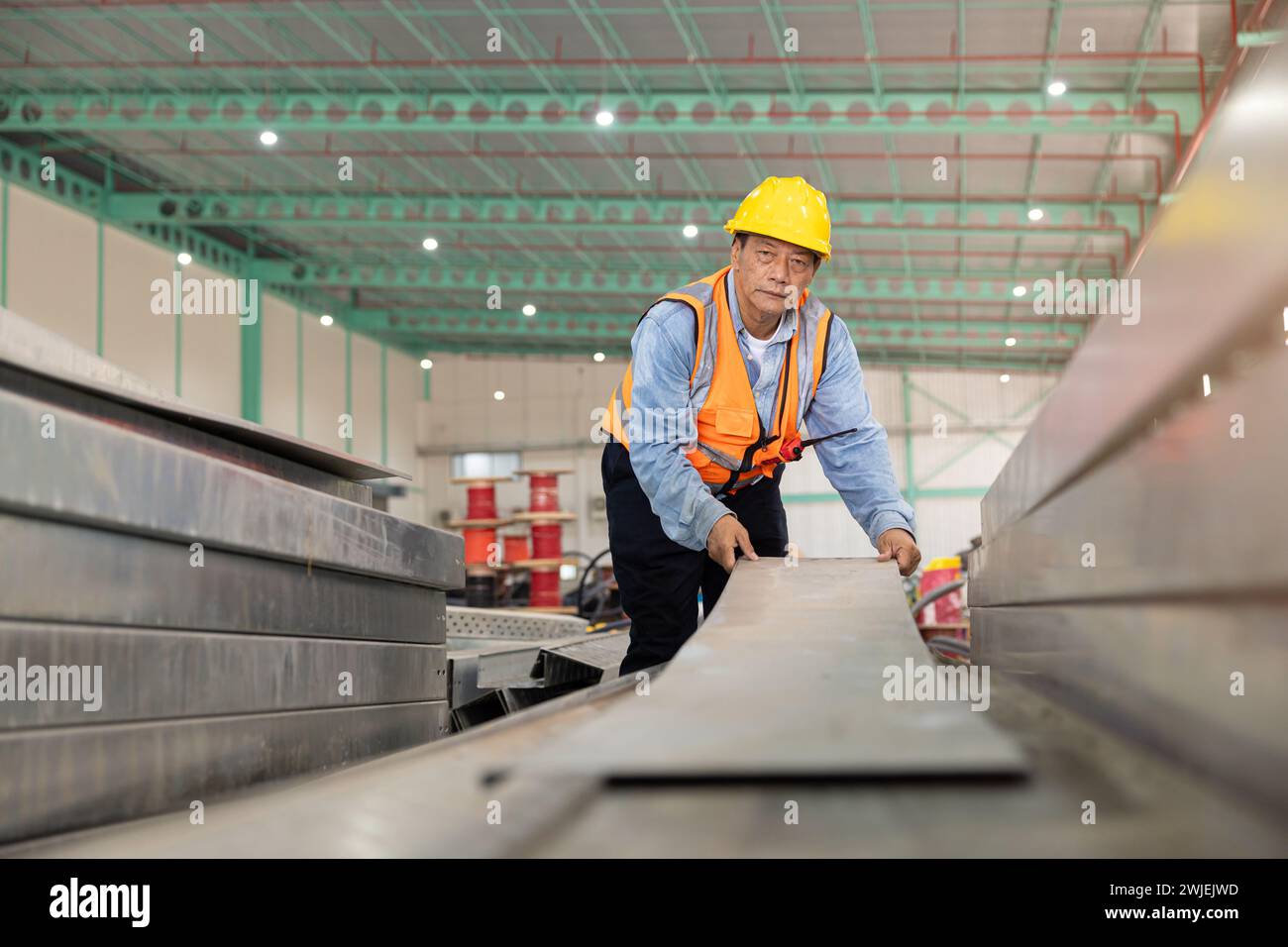 Der Bauingenieur installiert in großen Industriegebäuden eine Kabelkanalschiene aus perforiertem Metall. Blechfabrik Stockfoto