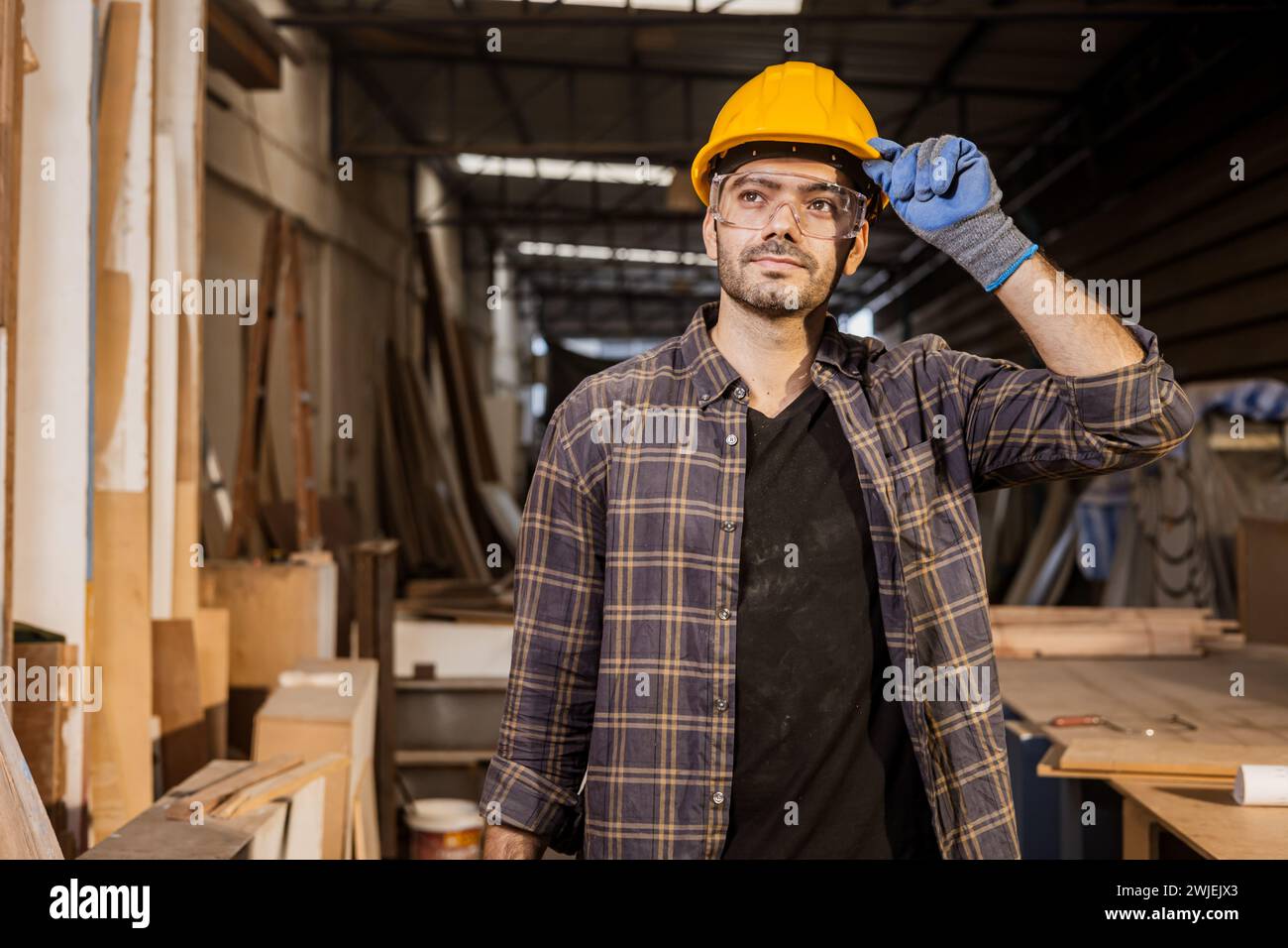 hispanischer indischer Zimmermann, der stolz darauf steht, Möbel in der Werkstatt herzustellen Stockfoto