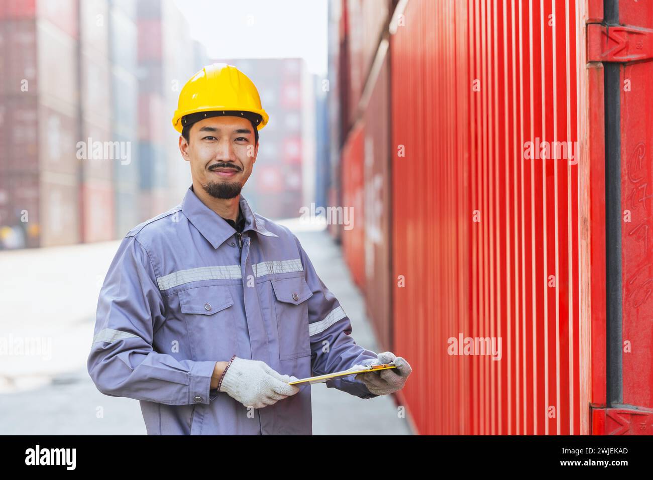Japanischer, intelligenter Arbeiter, der in der Containerladung arbeitet. Zollpersonal der japanischen Versandlogistik. Stockfoto