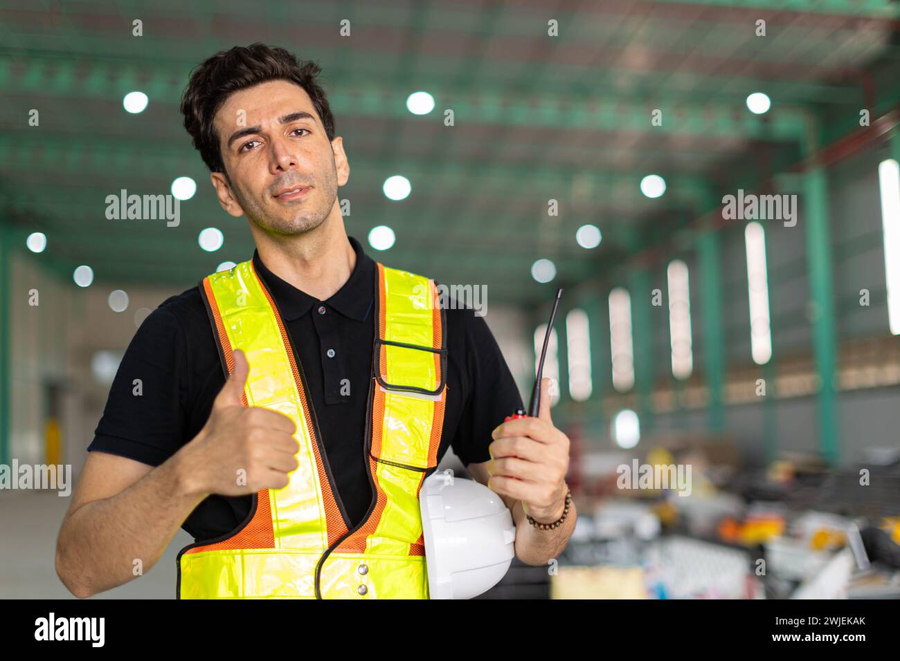 Ingenieur Mann Hand wie Schild oder Fabrikarbeiter tragen Sicherheitshelm in der Lagerhausstelle innen zeigt Daumen hoch Happy Smile. Gute Arbeit erledigt Stockfoto