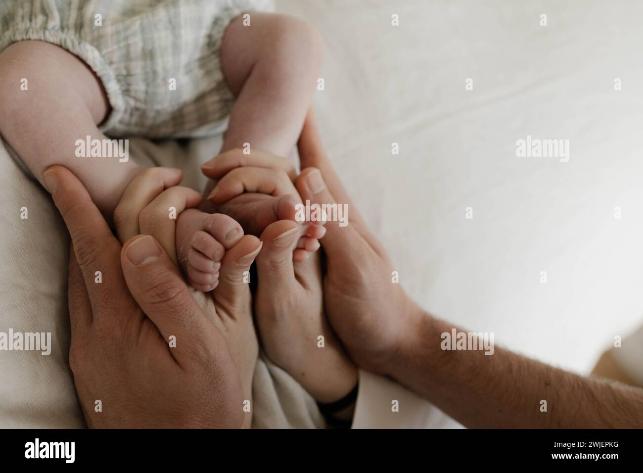 Neugeborene Füße, die von den Elternhänden gehalten werden Stockfoto