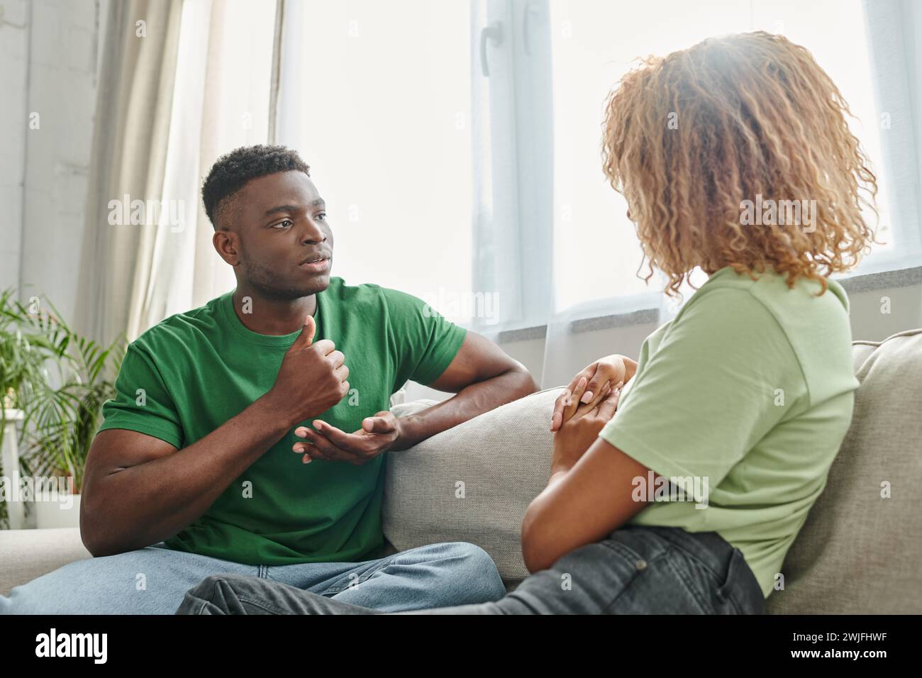 afroamerikaner zeigt Hilfe, während er mit Gebärdensprache in der Nähe seiner Freundin kommuniziert Stockfoto