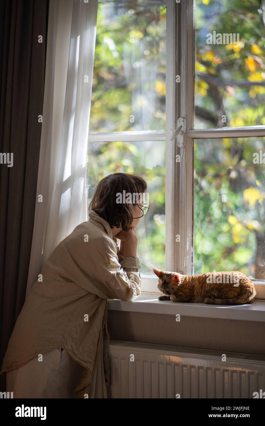 Melancholischer Haustierbesitzer, der in Depressionen auf das Fenster blickt, während er an sonnigen Sommertagen zu Hause bleibt Stockfoto