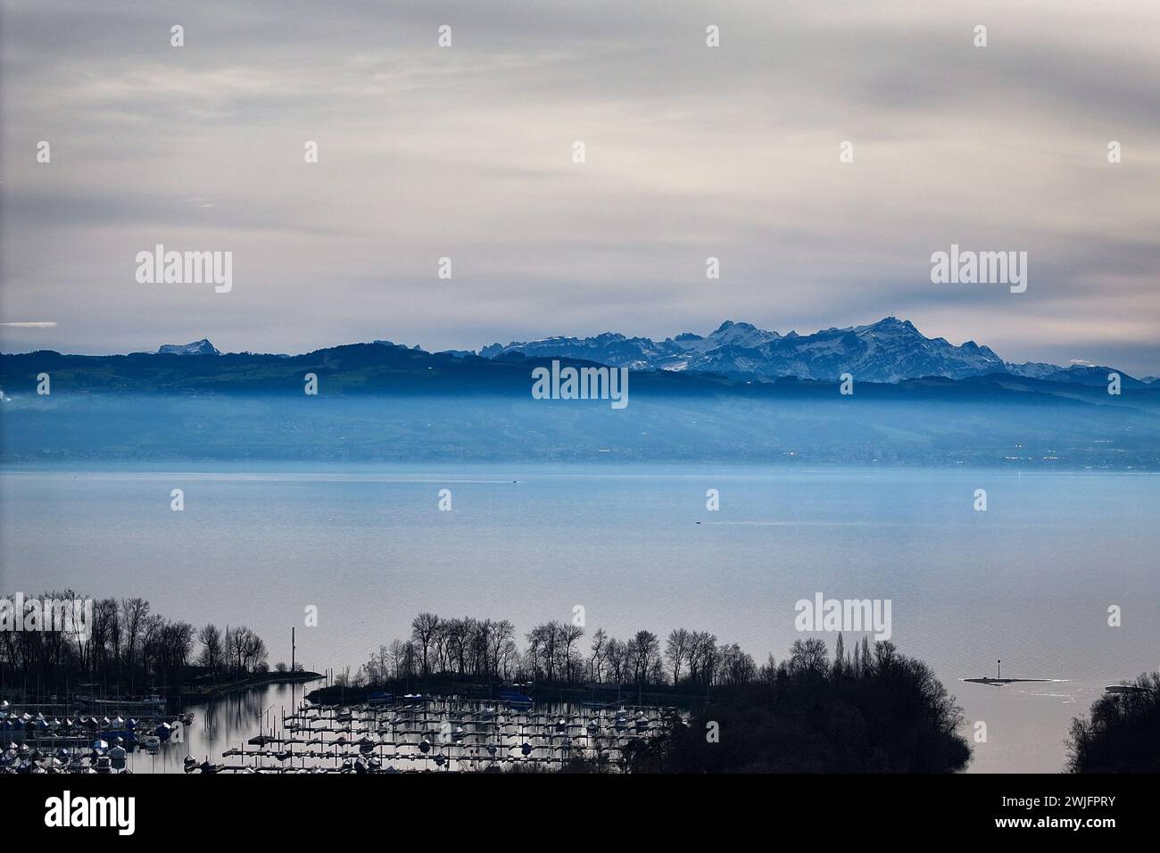 Langenargen, Deutschland. Februar 2024. Der Säntis mit seinem Mast auf dem Gipfel erhebt sich über den Dunst hinter dem Bodensee. (Luftaufnahme mit einer Drohne) im Hintergrund ist die Schweiz zu sehen und im Vordergrund die Argen, die in den Bodensee mündet. Quelle: Felix Kästle/dpa/Alamy Live News Stockfoto