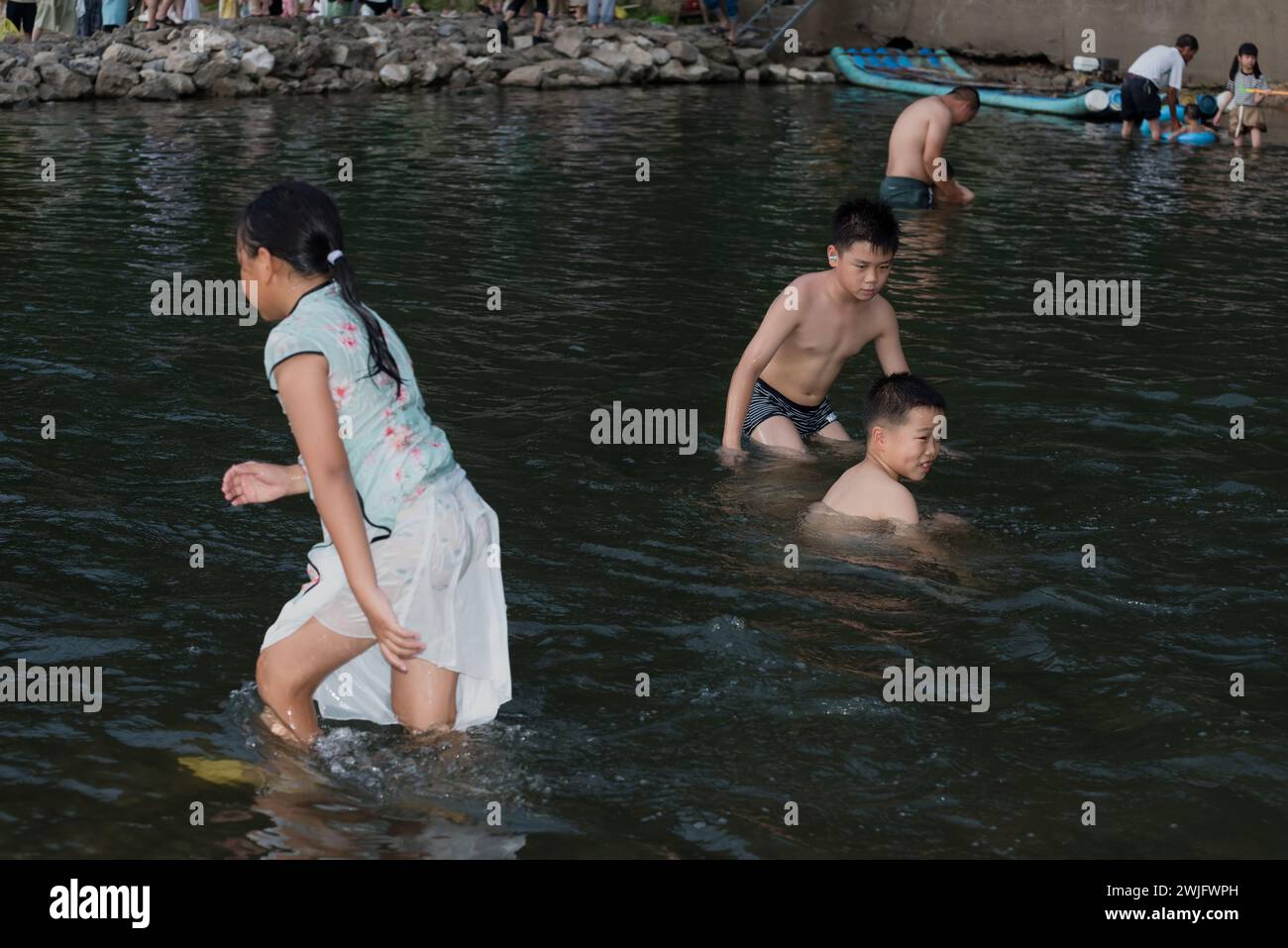 Yangshuo County, Guilin City, Guangxi, China - 5. August 2023: Kinder spielen an einem heißen Sommertag im Fluss Li Stockfoto