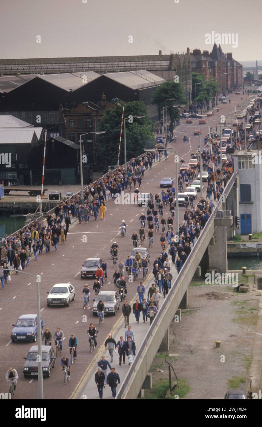 Am Ende ihrer Schicht verließen die Arbeiter von Vickers Shipbuilding and Engineering Ltd. Nach einem Tag Schiffsbauarbeiten nach Hause. Barrow-in-Furness, Cumbria, England um 1985. HOMER SYKES AUS DEN 1980ER JAHREN Stockfoto