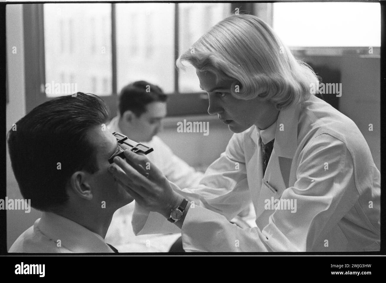 Eine nicht identifizierte Medizinstudentin an der Pritzker Medical School der University of Chicago verwendet ein Instrument, um die Augen einer anderen Studentin zu untersuchen, Chicago, Illinois, 18.11.1959. (Foto: Charlotte Brooks/LOOK Magazine Collection/LOC) Stockfoto