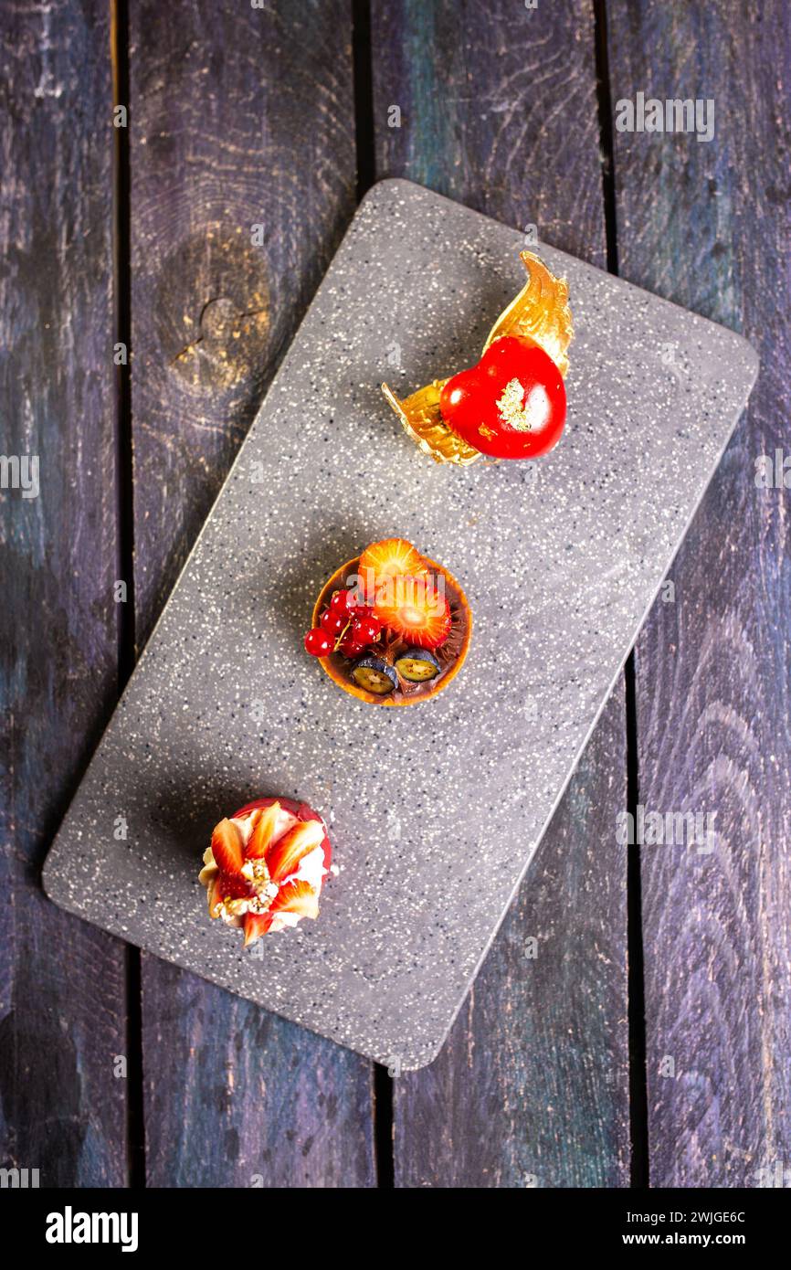 Eine exquisite Präsentation von vier dekadenten Kuchenscheiben, die elegant auf einem eleganten Marmorbrett angeordnet sind und ein Gefühl kulinarischer Opulenz wecken. Stockfoto