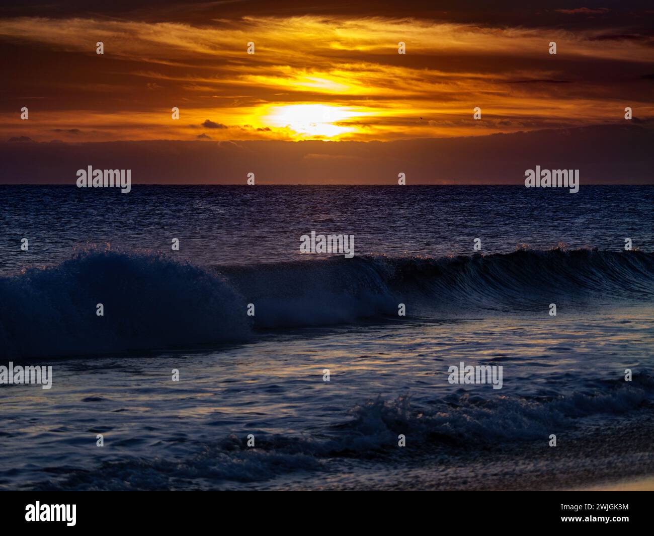 Wunderschöner Sonnenuntergang mit Wellen und Wolken Stockfoto