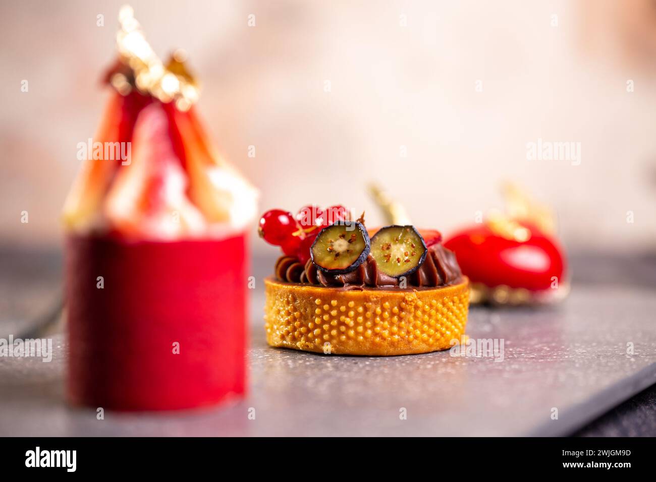 Köstliche Schokoladentorte, Erdbeermousse, Himbeermakronen auf Schieferbrett mit rosafarbenem Hintergrund für eine elegante Dessertpräsentation. Stockfoto