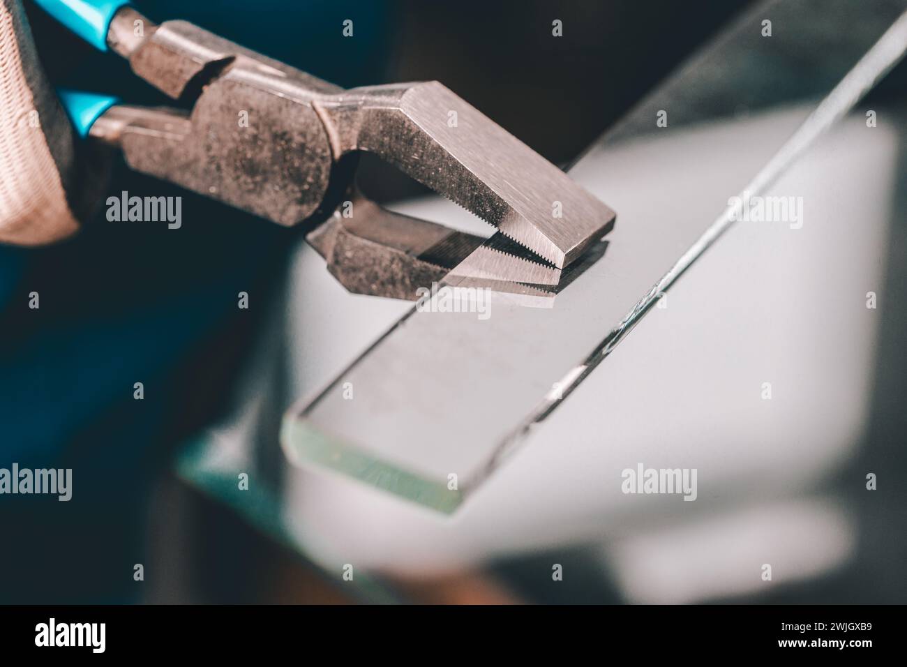 Schneiden und Abbrechen kleiner Glasstücke in einer Glasfabrik, Spezialwerkzeuge einer Glaserei, Glasfabrik Stockfoto