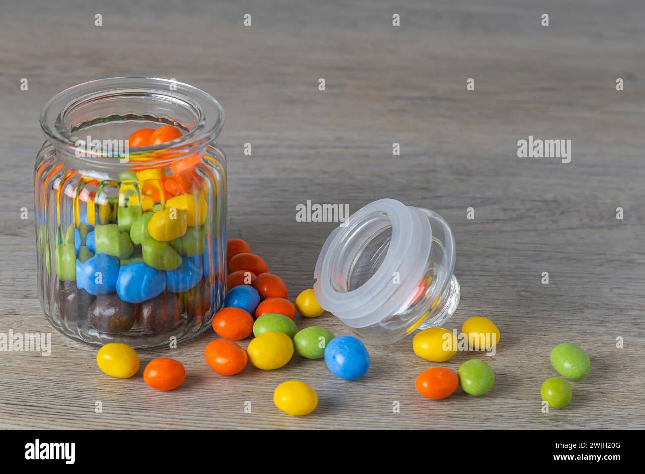 Erdnüsse in mehrfarbiger Glasur in einem Glas auf einem Holztisch Stockfoto