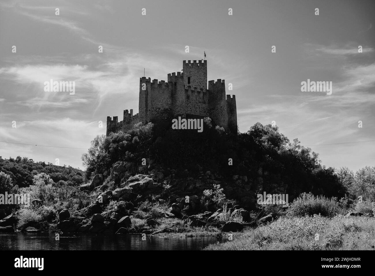 Ein Schwarzweißfoto von Almourol Castle und Bach eingebettet in eine waldreiche Landschaft Stockfoto