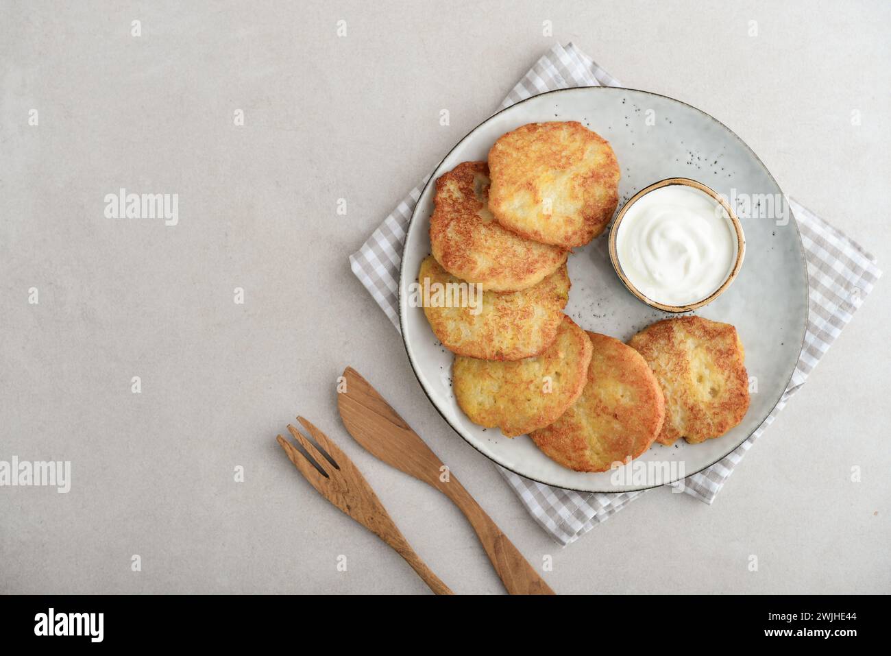 Kartoffelpfannkuchen oder Latkes oder Draniki mit Sauerrahm in Teller auf hellem Hintergrund. Draufsicht. Kopierbereich. Stockfoto