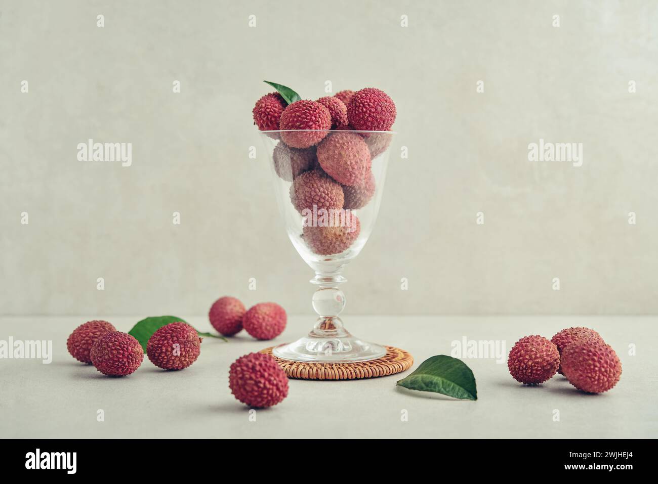 Frische Bio-Litschi-Frucht auf hellem Hintergrund. Litschi im Glasbecher als Hintergrund. Stockfoto