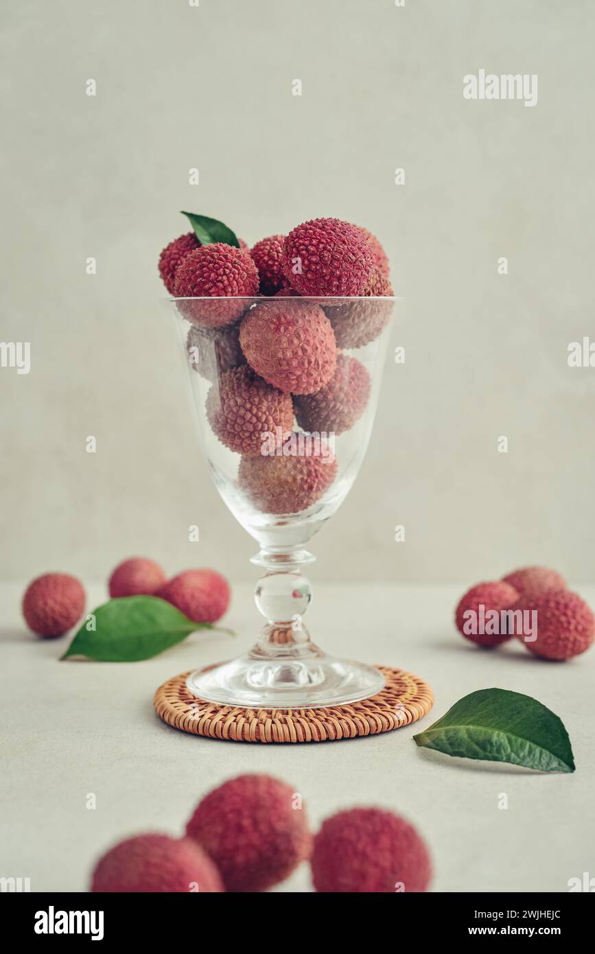Frische Bio-Litschi-Frucht auf hellem Hintergrund. Litschi im Glasbecher als Hintergrund. Stockfoto