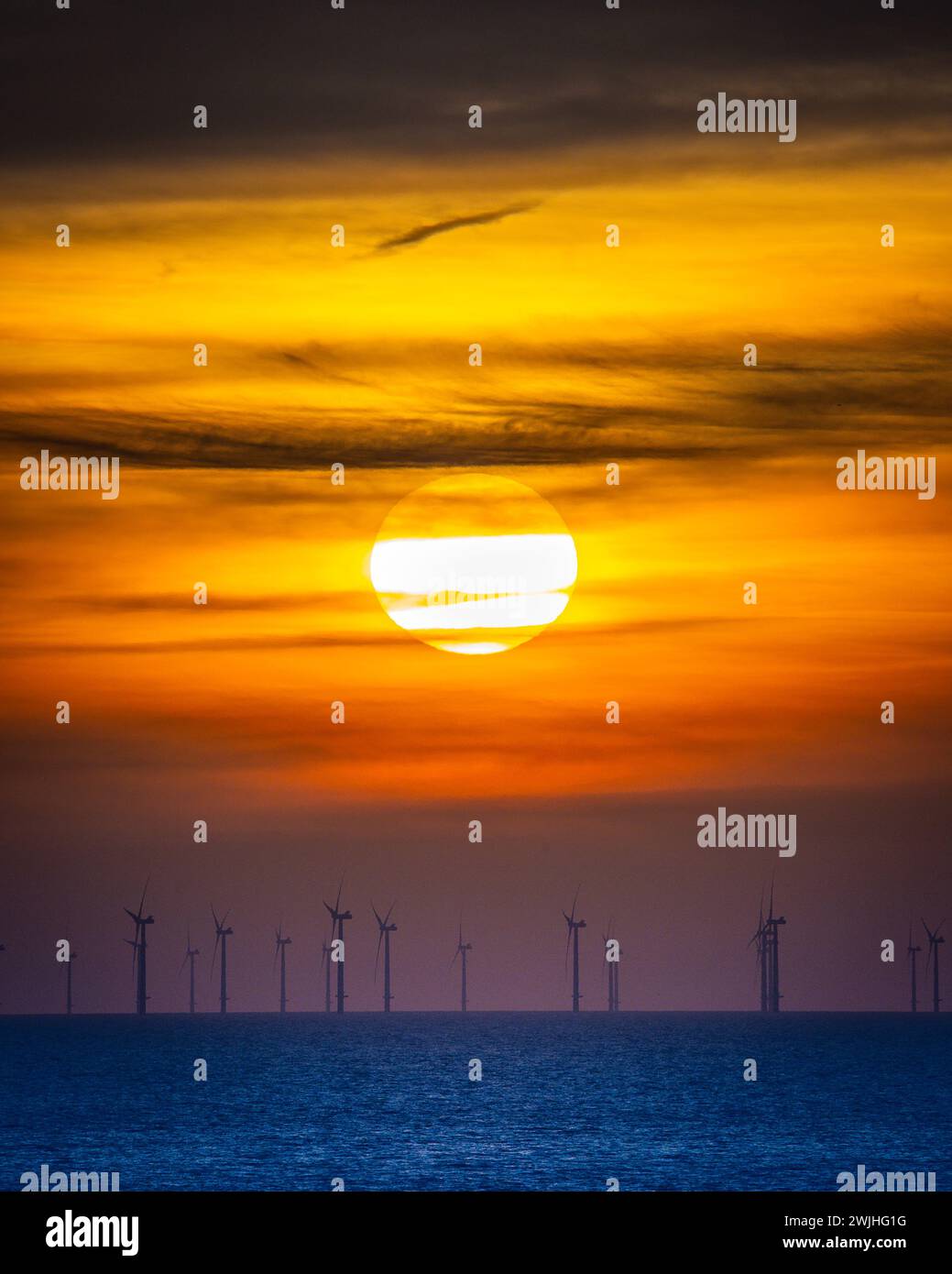 Sonnenuntergang über einem Windpark am Meer Stockfoto